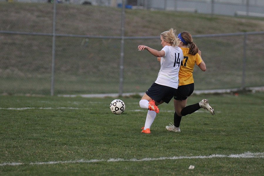With a defender putting pressure on her, senior Adde Hinkle shoots a half volley.