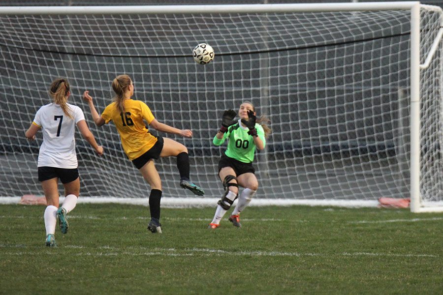 While preparing to catch the ball, senior goalkeeper Bailey Heffernon is put under pressure by an opposing player.