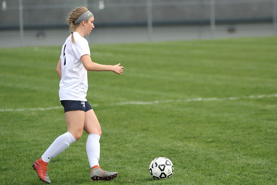 Preparing to pass the ball back, sophomore Emerson Kaiser looks down to focus on the pass.