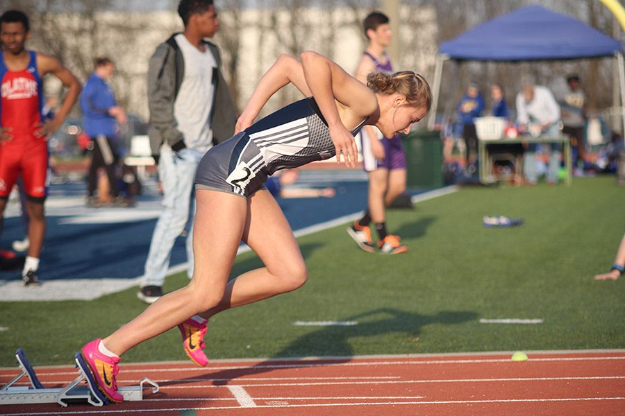 Throwing her arms back, senior Bella Hadden starts the 400 meter dash at the Olathe Invitational on Thursday, April 5. 