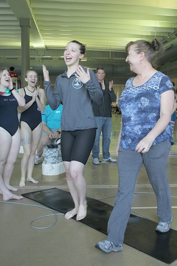 Senior Jordan Robinson walks with her mother as she is applauded by her teammates.