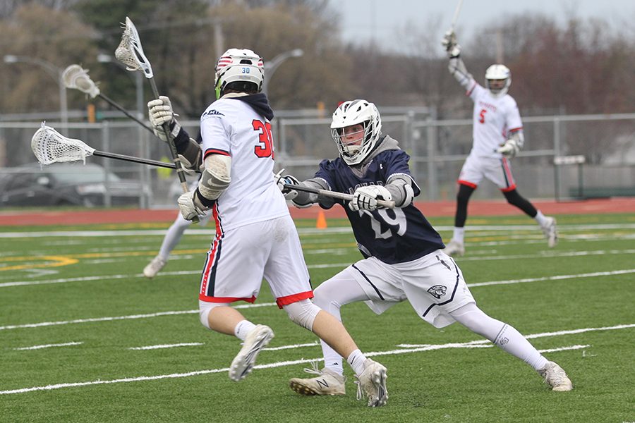 In attempt to cause his opponent to drop the ball, senior Camden Commerford hits him with the stick.