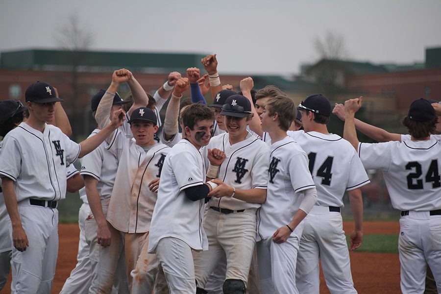 Raising their hands, the baseball team celebrates after the game.