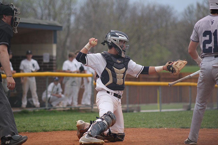 Coming onto one knee, junior Ethan Judd prepares to throw the to ball back to the pitcher.