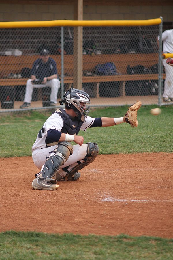 Extending his mitt, junior Ethan Judd catches a pitch from junior Nolan Sprague.