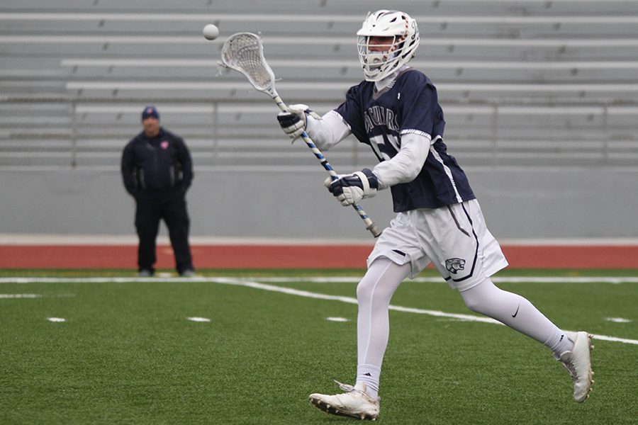 While running down the field, sophomore Ethan Mantel passes the ball to a teammate.