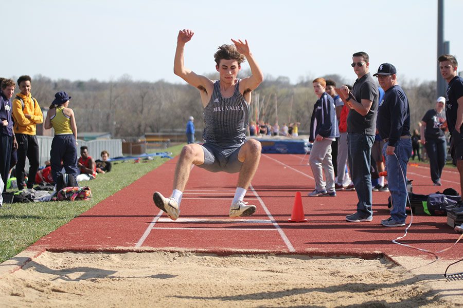 Hands forward, sophomore Anthony Runk leaps into the long jump pit.