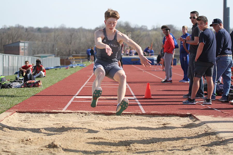 Junior Harry Ahrenholtz finishes his long jump, in which he placed first.