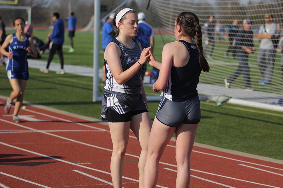 After the 1600 meter, senior Christine Lust high fives junior Delaney Kemp.