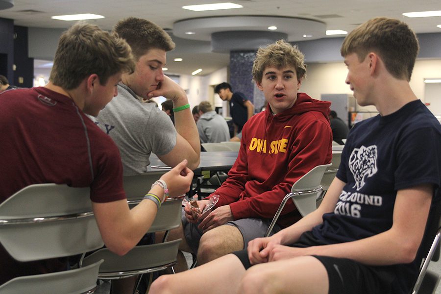As part of his morning routine, junior Logan Talley eats banana bread and talks to juniors Steven Colling, Ryan Bauer and Harry Ahrenholtz before school on Tuesday, April 17.