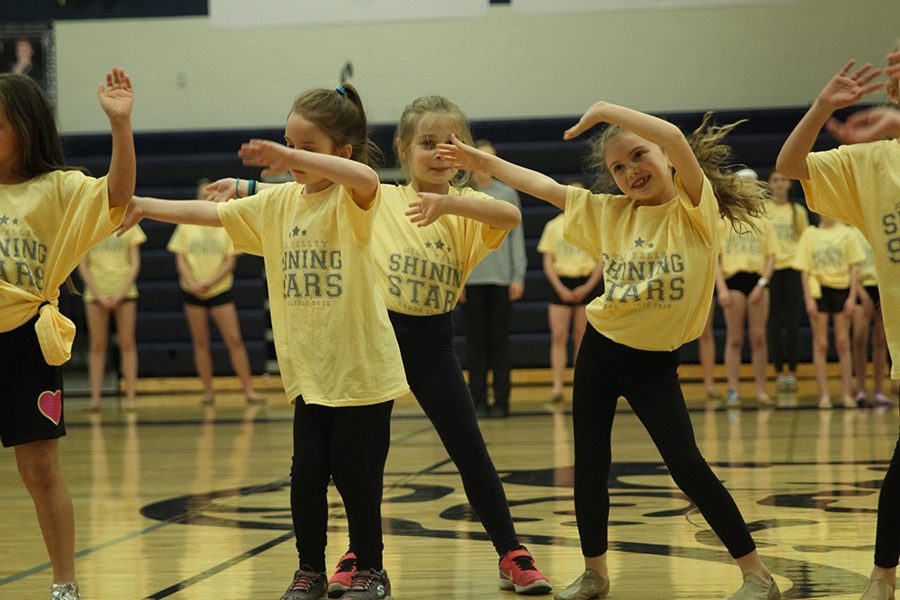 Waving their hands up in the air, community members dance in in the Shining Stars routine. 