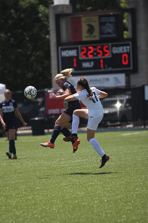 Jumping in the air, senior Adde Hinkle kicks the ball to her teammate. 