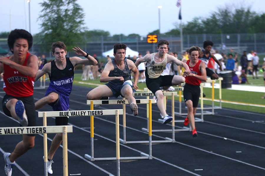 Looking down the track, junior Wyatt Leonard jumps over a hurdle at the EKL league meet on Friday, May 11 at Blue Valley High School. 