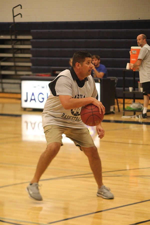 Stepping back from a defender, physical education teacher Travis Keal dribbles the ball.