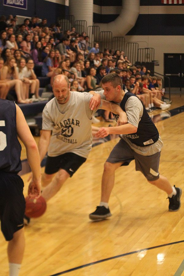 Defending against senior Mason Cole, graphic design teacher Jerry Howard dribbles towards the basket.
