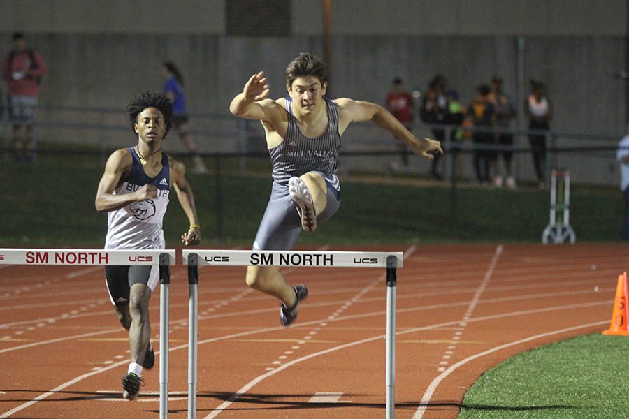 During the 300m hurdles, junior Eli Midyett leaps over a hurdle.