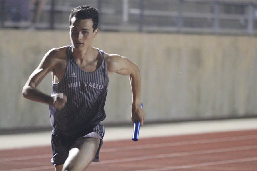While running in the 4x400, junior Matthew Turner runs with baton in hand.