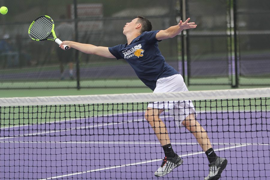 In attempt to reach the ball playing up at the net, junior Eric Schanker extends his racket to earn the point.