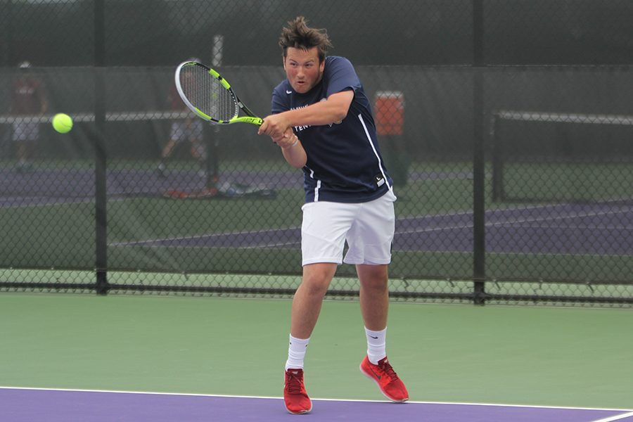 Competing in his first set of doubles, junior Jacob Hoffman does a two-handed backhand swing.