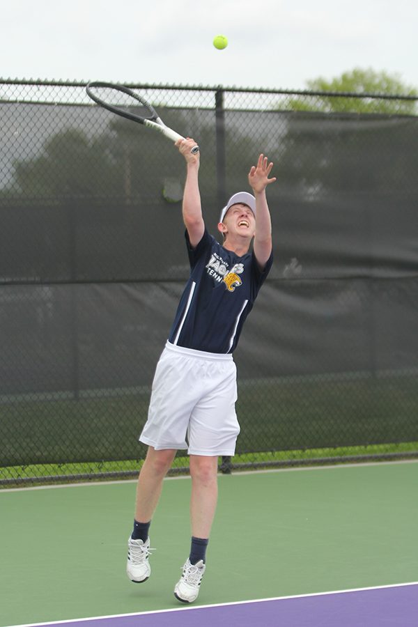 Keeping his eyes on the ball, senior Landon Butler serves the ball.