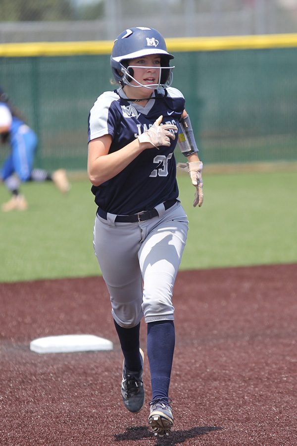 Keeping her eye on members of the opposing team, junior Grace Lovett prepares to run into third base. 
