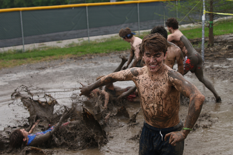Running away, senior Max Whisler smiles as his friends fall in the mud.