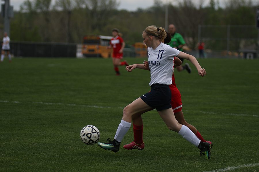 Kicking the ball past her opponent, junior Kendra Bross runs towards the goal.