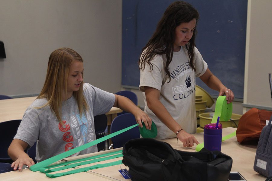 Senior Adelle Warford and junior Cristina Talavera work on cutting streamers for Homecoming week decorations.