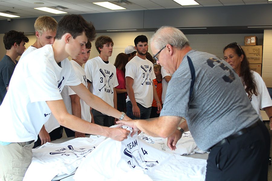 After organizing the t-shirts in order by size, senior Devin Bly hands someone a shirt. 