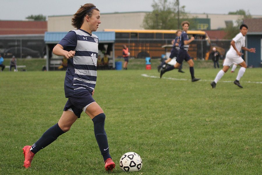 Running towards the rest of the team, sophomore Quinten Blair travels down field with the ball. The team won 2-1 against Blue Valley North West on Tuesday Sept. 25. “It’s always a great battle against the Blue Valley schools and to get the win against such a good school really gives our reputation a boost,” Blair said.