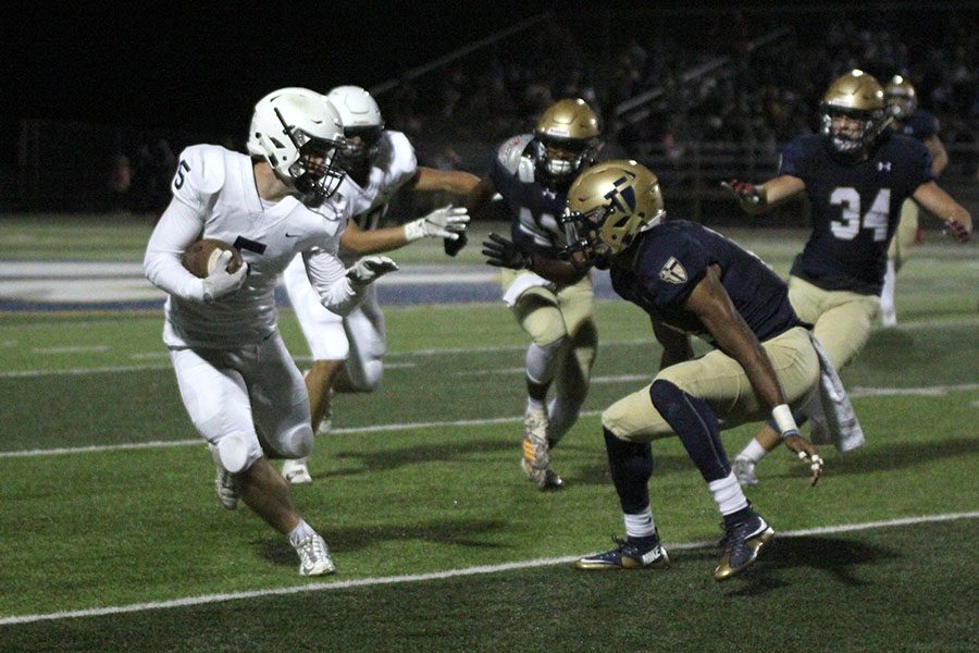 Redirecting his path, senior Logan Talley avoids Aquinas defenders to advance the ball on Friday, Sept. 21. The Jaguars fell to the Saints 24-13. 
