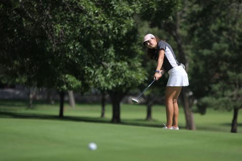 Standing on the green, senior Sarah Lawson uses her putter to hit the ball.