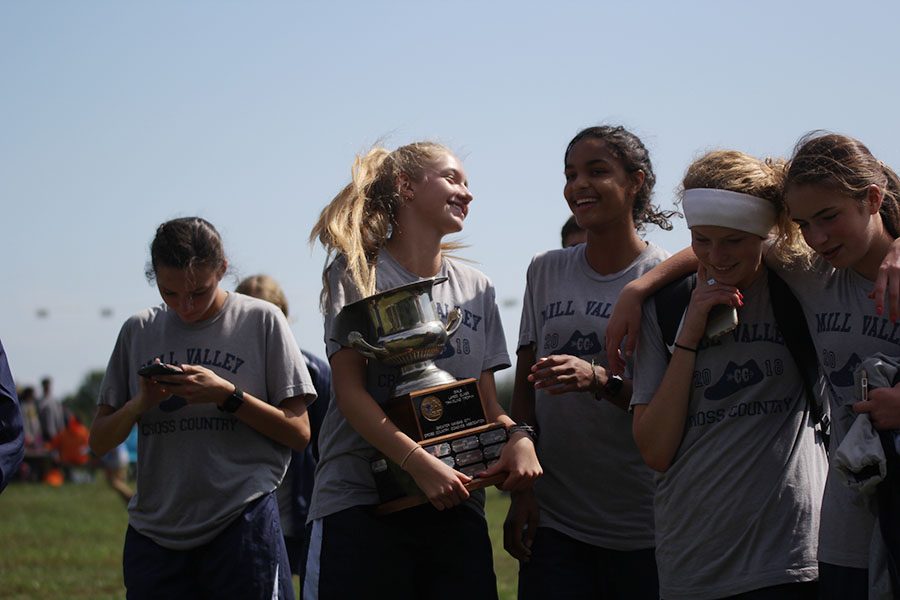 Concluding the awards ceremony, sophomores Josie Taylor and Madison Page smile with the first place trophy in their possession on Saturday, Sept. 29 at the Rey-Pec cross country course. The team works together by backing it up, Taylor said. Every single person matters on the team whether you come in first for our team or 10th.