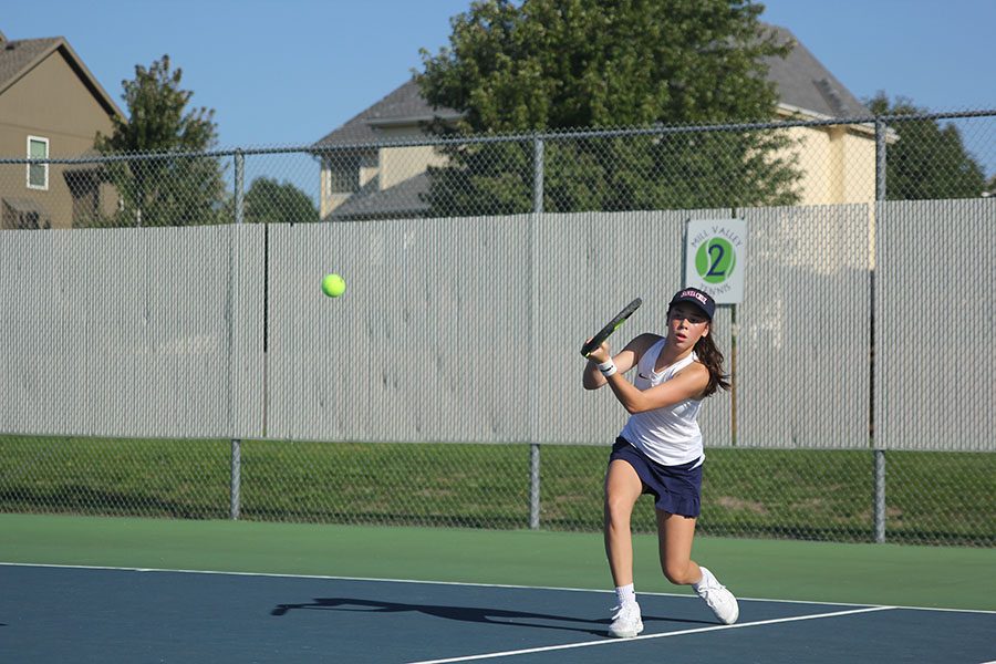 Bending down, freshman Eden Schanker returns the ball to the opposing team.