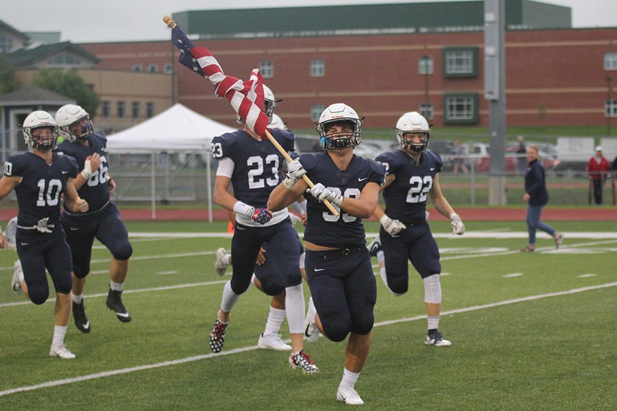 Running out onto the field, senior Trevor Wieschhaus waves the American flag.
