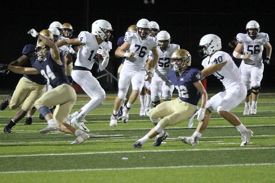 As senior wide receiver Dustyn Sweet grabs a Saints defender, senior wide receiver Matt Wittenauer pushes past an Aquinas player to run the ball downfield.