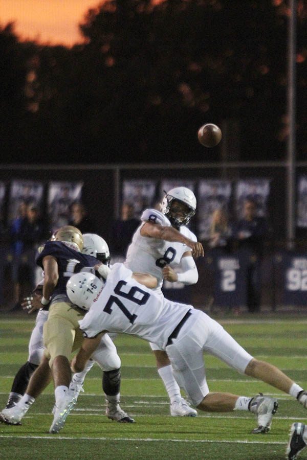 As junior offensive lineman Kyle Kelly tackles a Saints defensive player, senior quarterback Jordan Preston throws the ball downfield. 