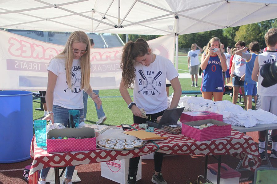 Under the fundraising tent, senior Lexi Ballard and junior Brynn Ayers help register teams and sell Team Nolan gear.