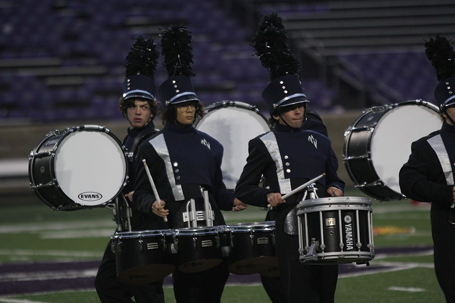 Playing their respective instruments, members of the drumline march onto the field.
