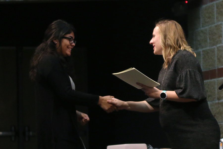 Shaking English teacher Page Anderson’s hand, senior Fatima Hernandez is inducted into National English Honors Society on Wednesday, Oct. 10 in the Little Theater. 
