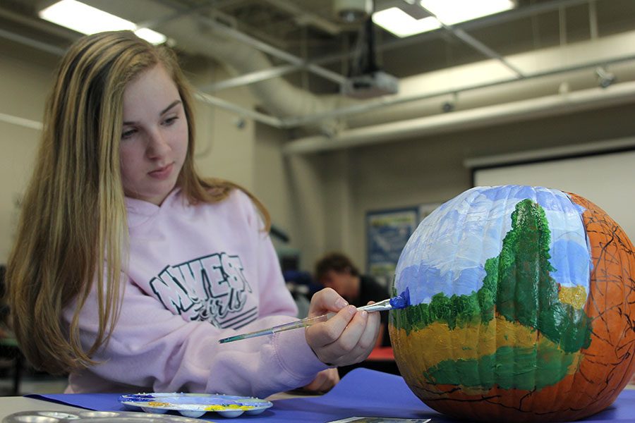 On Wednesday, Oct. 31 art teacher Jodi Ellis drawing students replicate famous paintings onto pumpkins, for a fun and festive twist. Painting a pumpkin, sophomore Courtney Zymball recreates Wheat Field with Cypresses by Vincent Van Gogh. 