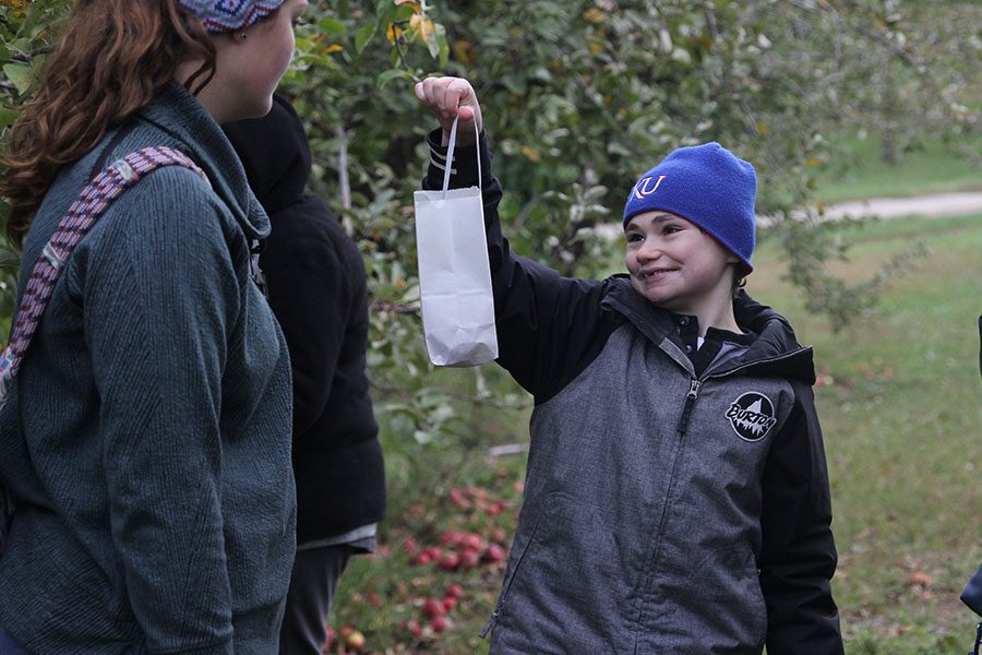 Holding up his bag, sophomore Charlie Peterson shows senior Makayla King his newly picked fruit.