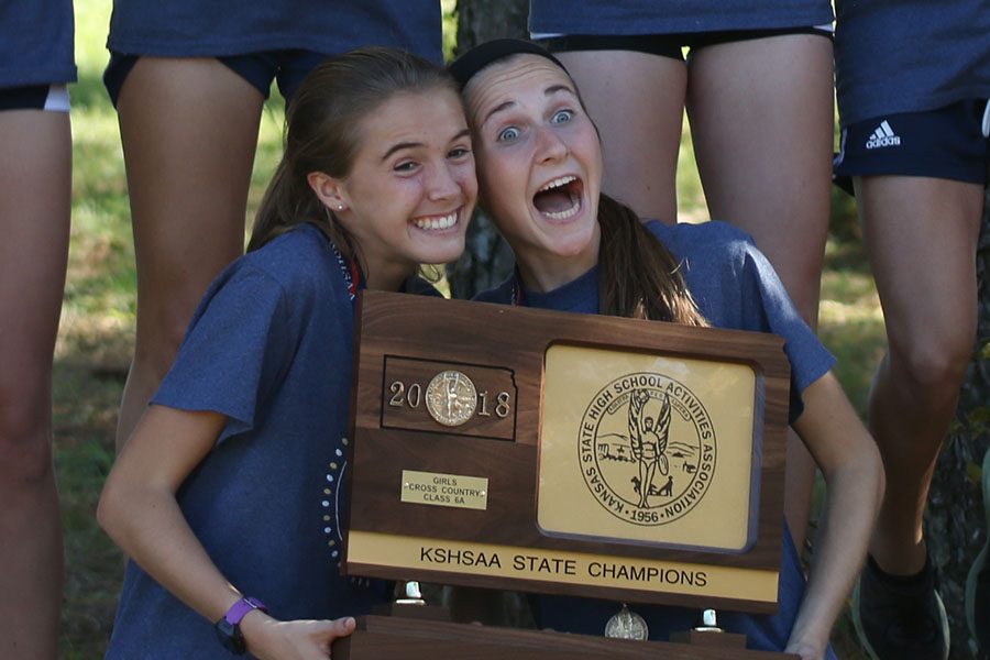 With an excited smile, juniors Molly Haymaker and Morgan Koca hold the state championship trophy together.