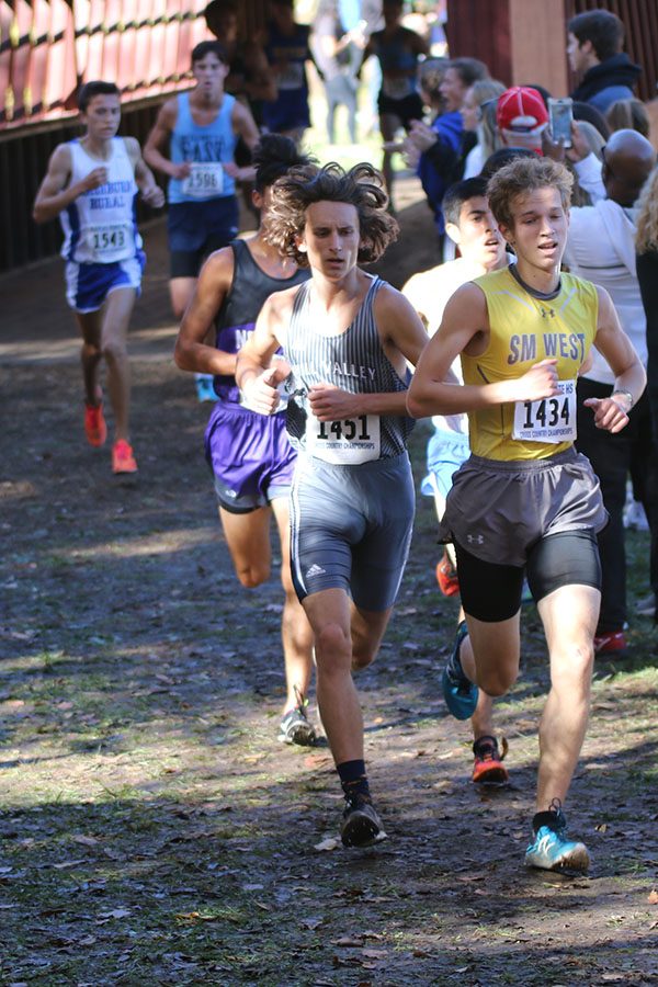 With his hair blowing in the wind, junior Darius Hightower looks to pass a Shawnee Mission West runner.