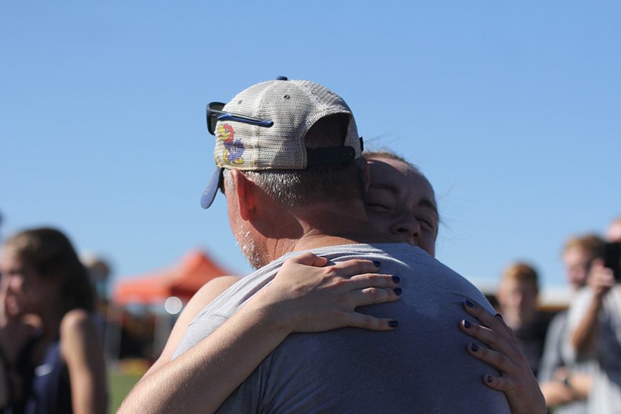 Moments after their placing is revealed, senior Delaney Kemp gives head coach Chris McAfee a big hug.