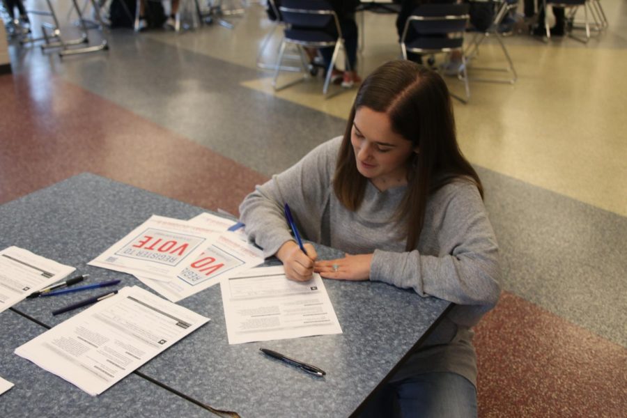 Kneeling down, senior Hannah Barnes finishes filling out her registration form.