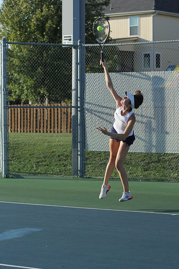 Clearing the ground, sophomore Sophie Lecuru serves the ball during her singles match.