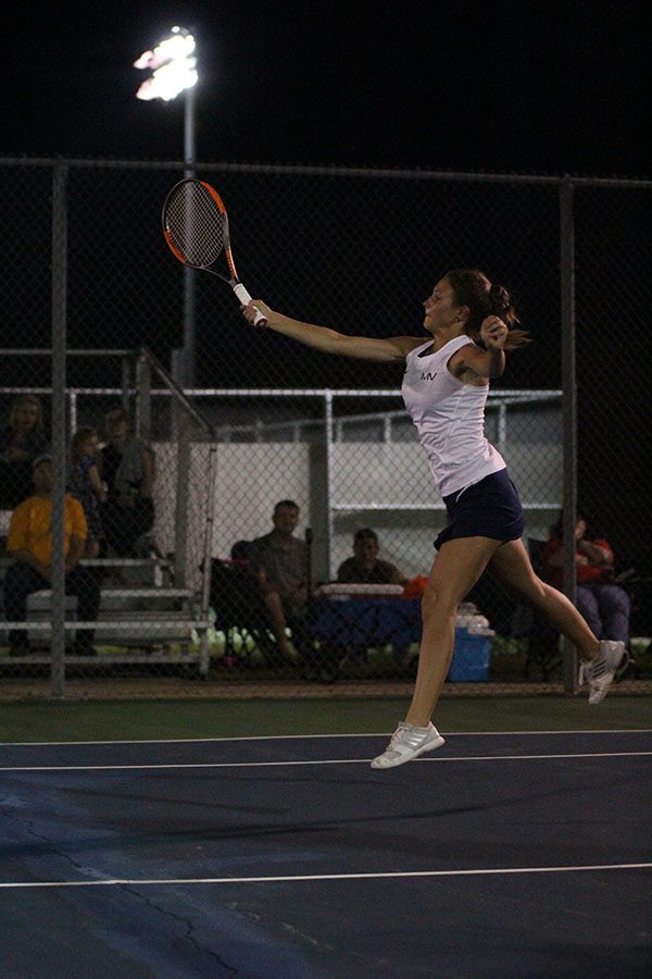 Jumping up, junior Avery Altman attempts to hit the oncoming tennis ball.