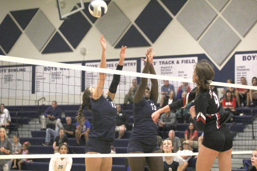 With the opponent trying to block the hit, sophomore Molly Carr, attempts to score a heavily contested point against 6A opponent Blue Valley West on Tuesday, Sept. 11. 