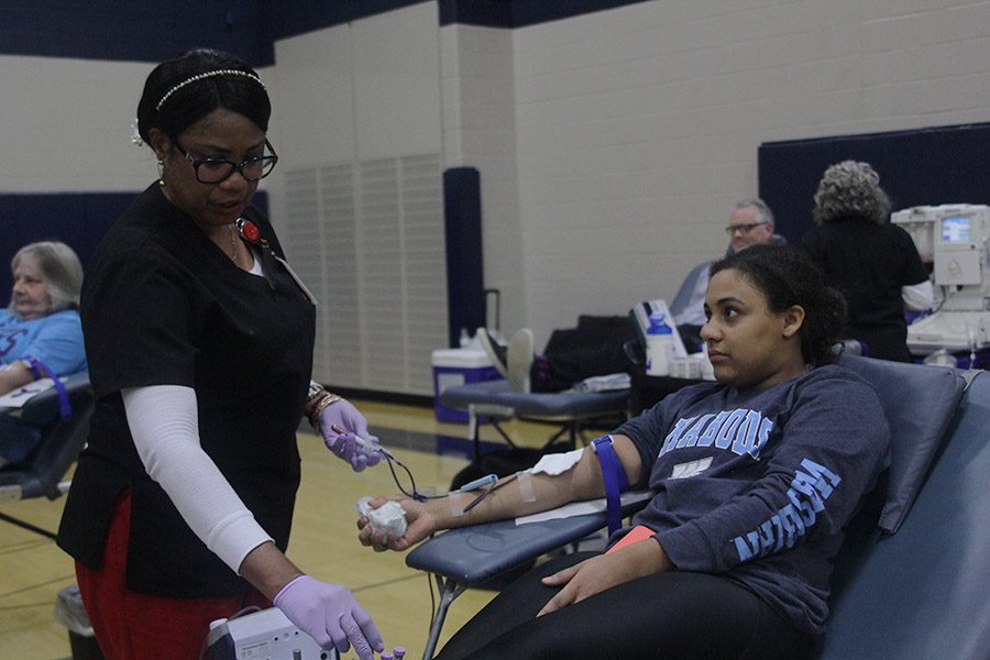 While watching the blood drive worker, senior Sydney Pullen donates blood.